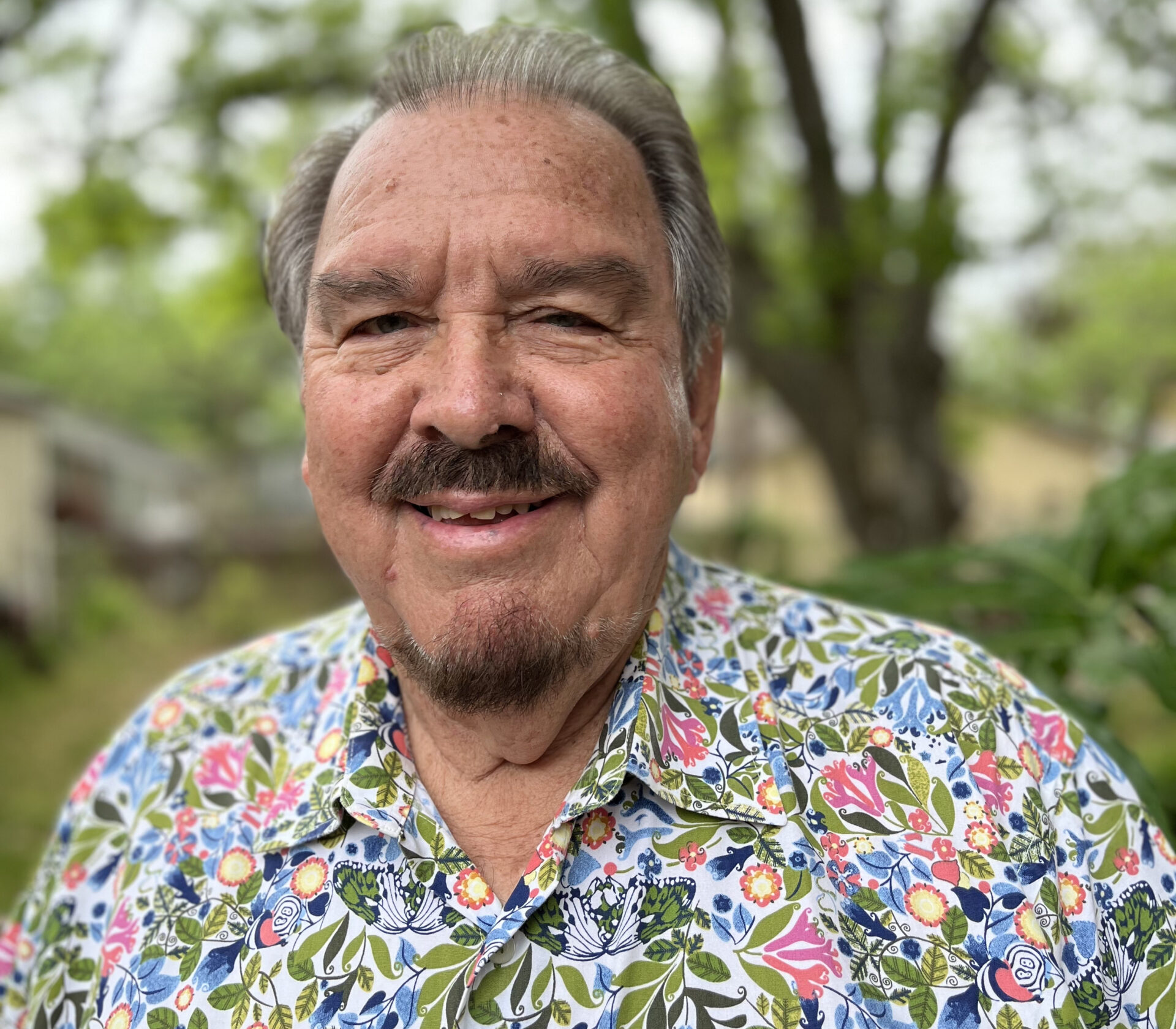 A headshot of Richard Martinez smiling outdoors in front of trees.